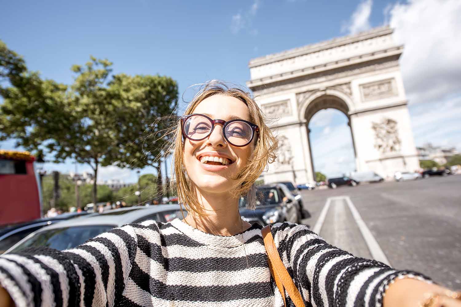 Woman traveling in Paris Young woman tourist making selfie portrait with famous Triumphal Arch on the background in Paris